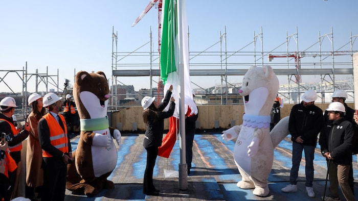 Elle procède à la levée du drapeau en compagnie de dignitaires et des deux mascottes des Jeux.