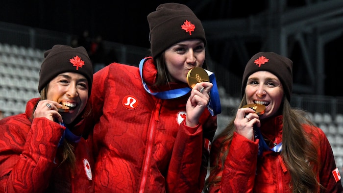 Les trois patineuses croquent dans leurs médailles.