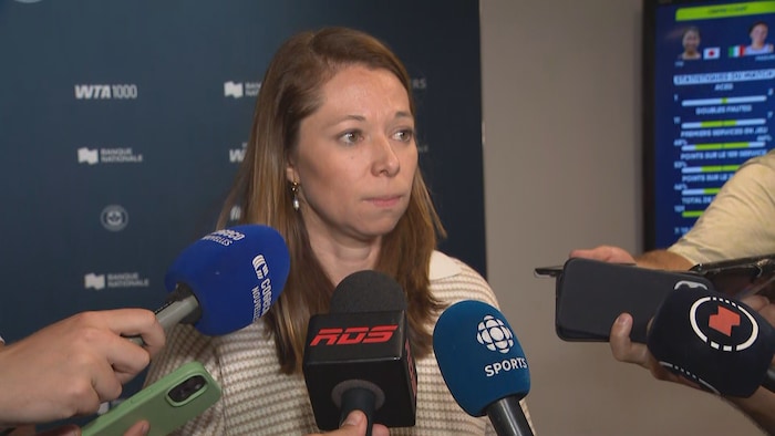 Elle écoute une question d'un journaliste.