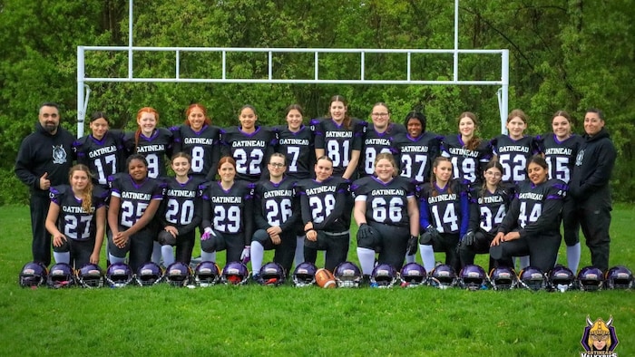 Des joueuses de football et leurs entraîneurs prennent la pose pour une photo d'équipe.