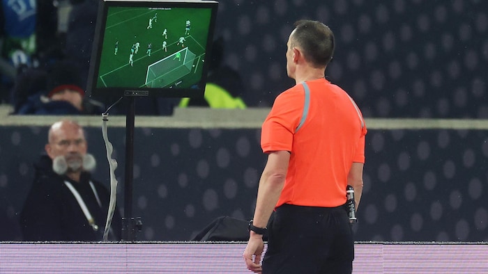 Un arbitre de soccer regarde une vidéo sur un petit moniteur.