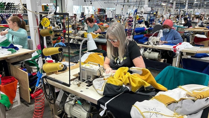 Des gens font de la couture dans une usine.