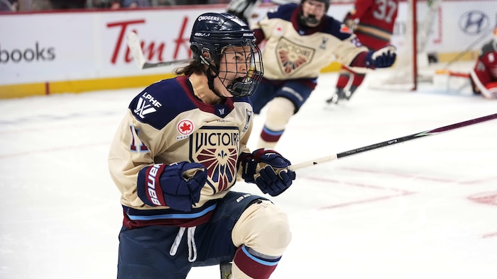 Une attaquante de hockey célèbre son but avec enthousiasme.