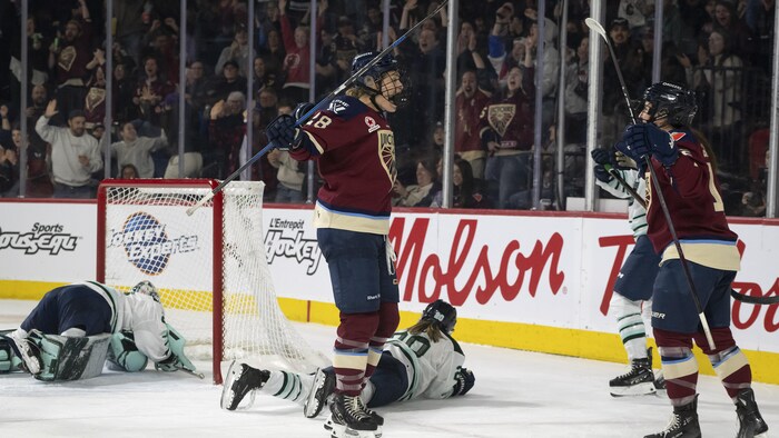 Deux joueuses de hockey célèbrent un but à côté du filet adverse. 