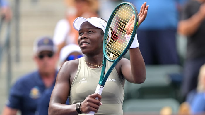 Une joueuse de tennis tape sa raquette d'une main.