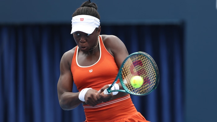 Une joueuse de tennis frappe une balle avec sa raquette.