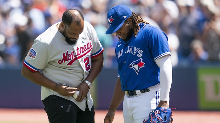 Vladimir Guerrero père signe une balle, sous le regard attentif de son fils.