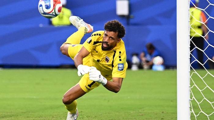 Un gardien de but tente d'arrêter un ballon de soccer.
