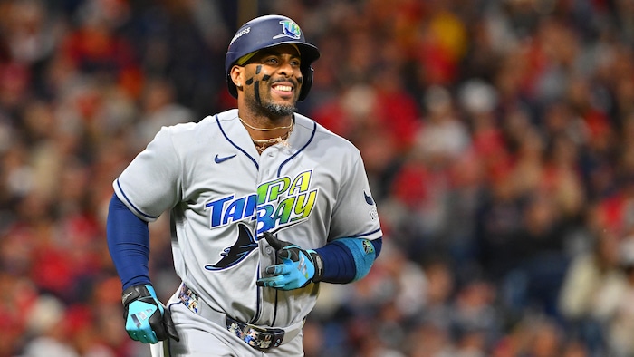 Un joueur de baseball court en souriant. 