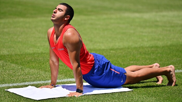 Le Britannique Adam Gemili fait une séance de yoga avant l'épreuve mixte du 400 mètres, au stade Todoroki, à Kawasaki, en mai 2019.