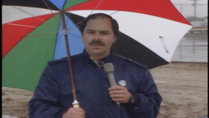 Homme moustachu avec un parapluie et un micro.
