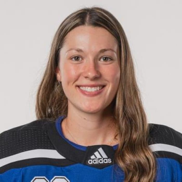 Une joueuse de hockey sourit.