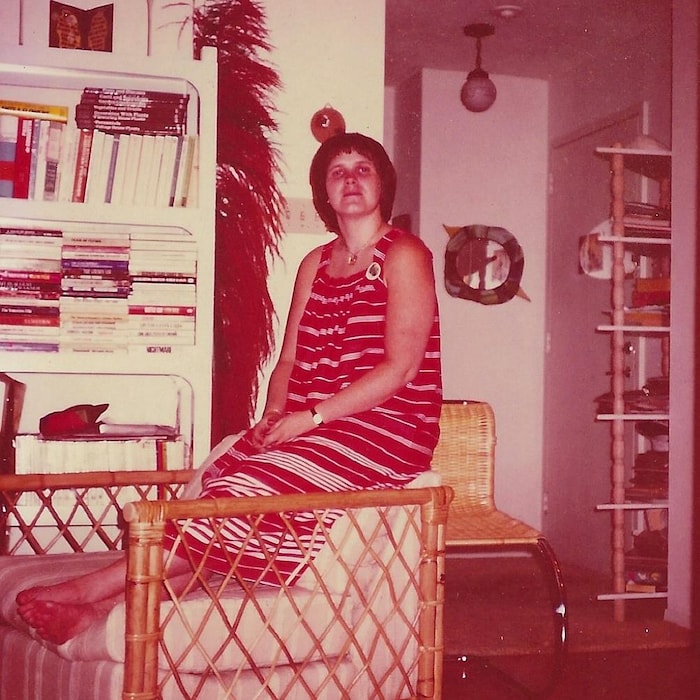Une femme est assise et regarde la caméra.