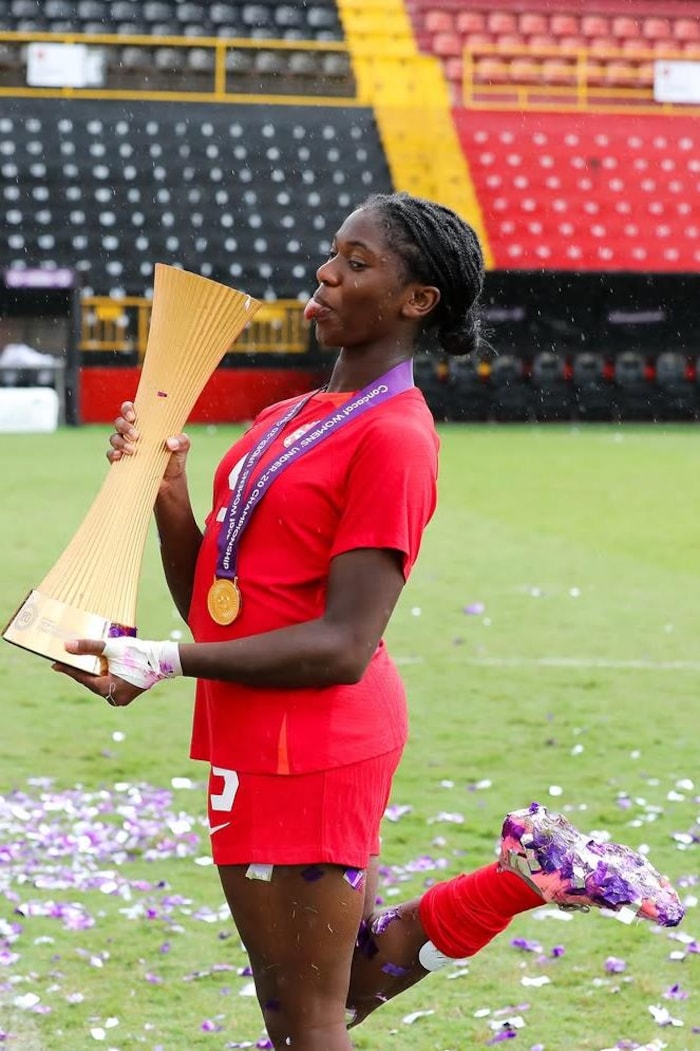 Elle tyre la langue en tenant le trophée dans ses mains.