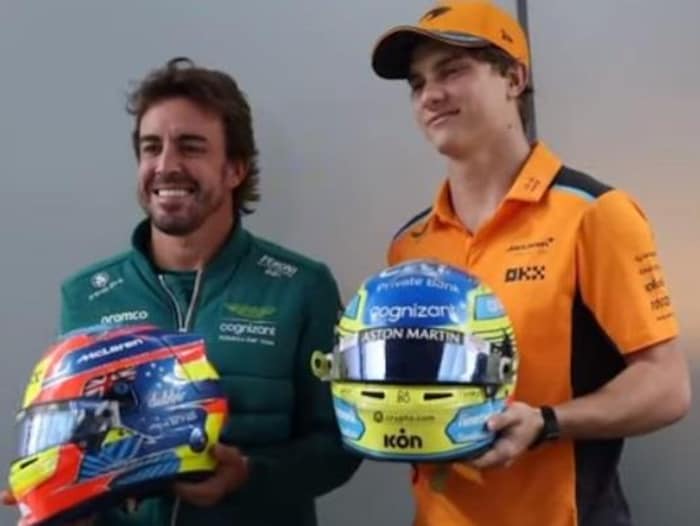 Deux pilotes de F1 s'échangent leur casque et sourient pour la photo.
