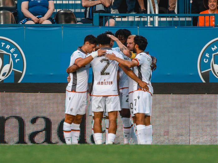 Six joueurs forment un cercle sur le terrain et se félicitent.