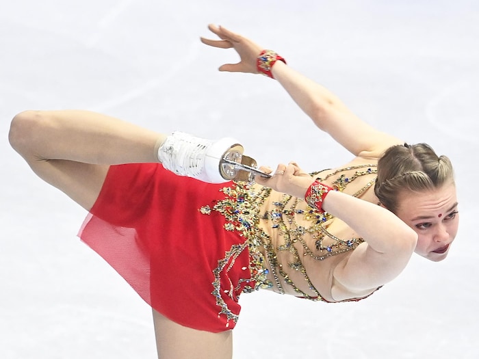 Une patineuse effectue une figure où elle tient son patin par la lame.