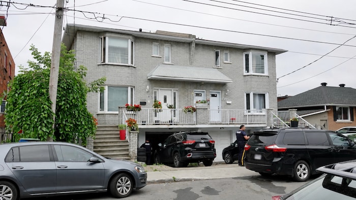 Des voitures de police banalisées devant un immeuble.