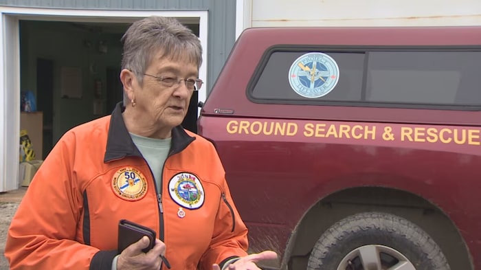 Portrait de Sherry Veinot, en veste orange devant un véhicule de Nova Scotia Ground Search and Rescue