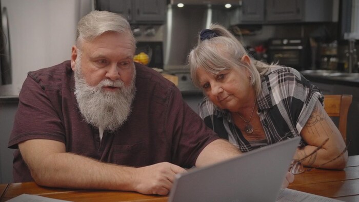 Un couple regarde l'écran d'un ordinateur. 