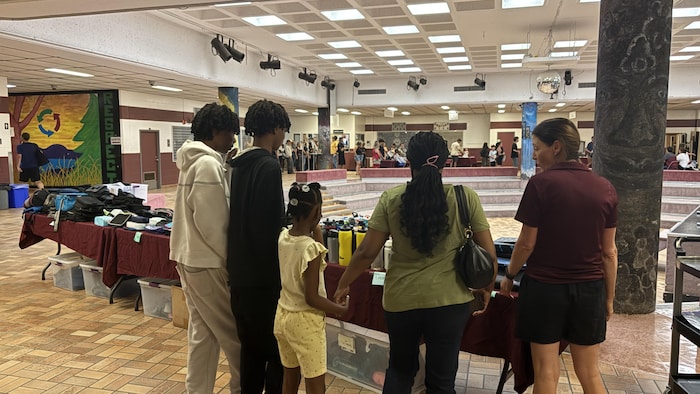 Une famille regarde les effets scolaires à vendre. 