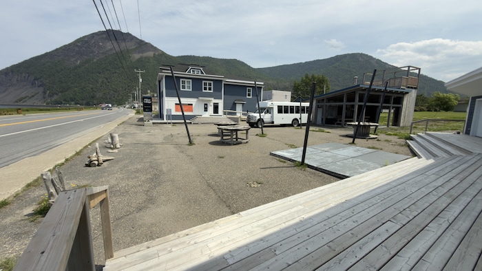 Une espace sans activité où se trouve des tables, un minibus et un bâtiment fermé.