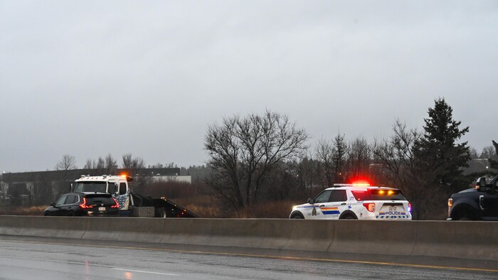 Des policiers et une remorqueuse sur une route congestionnée. 