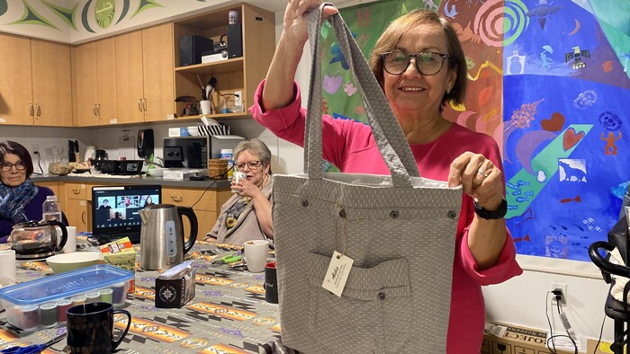 Une femme, Olga Lucía, du groupe de femmes hispaniques de plus de 50 ans, les Alelís, pose avec l'un des sacs qu'elle a confectionné elle-même.