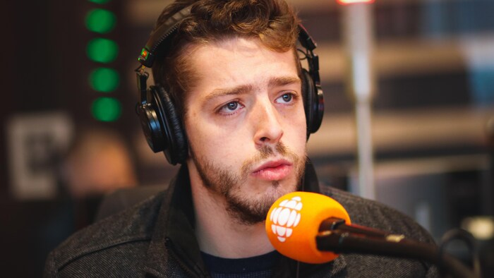 Alexandre Cédric Doucet au micro dans un studio de radio.