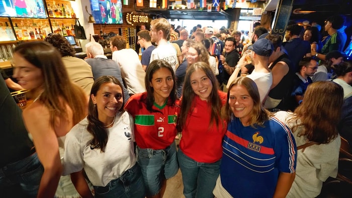 Quatre femmes, dont deux portent les couleurs de la France et deux, celles du Maroc, sourient à la caméra dans le bar.