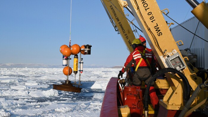Un instrument de mesure est installé dans l'eau glacée à l'aide d'une grue