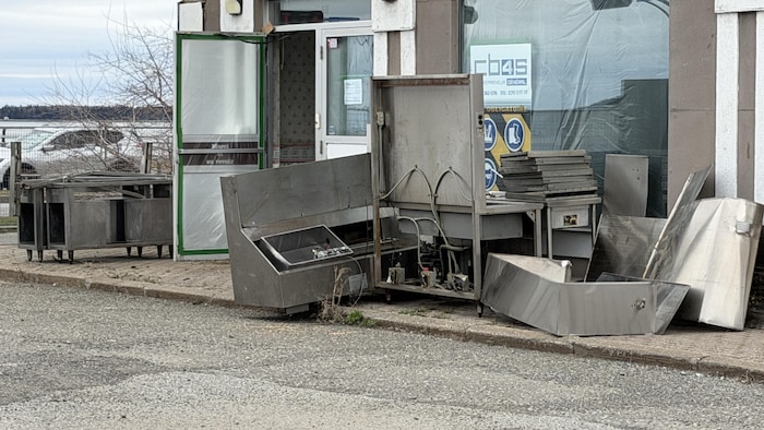 Des appareils de restaurations sont posés au sol à la sortie d'un bâtiment en voie d'être rénové.  