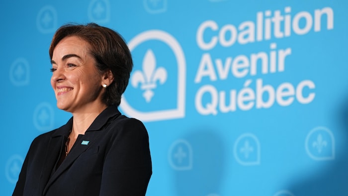 Christine Fréchette sourit devant un décor aux couleurs de la Coalition Avenir Québec.