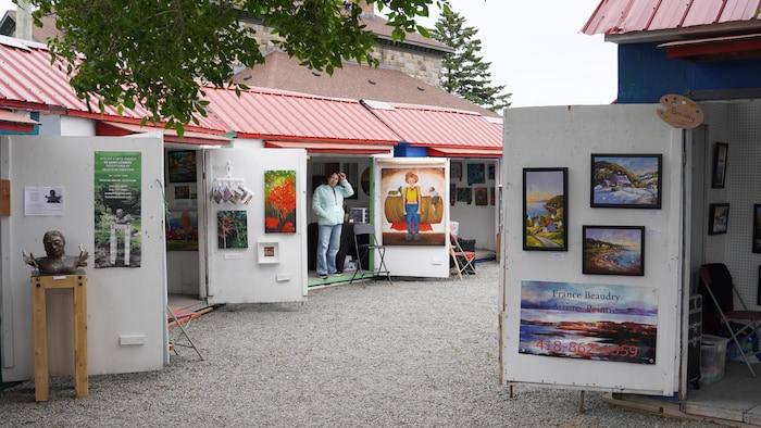 Des maisonnettes avec des toiles d'artistes peintres affichées et des sculptures exposées sur le seuil.