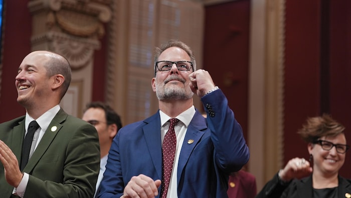 Alexandre Boulerice sourit et lève le poing dans les airs.