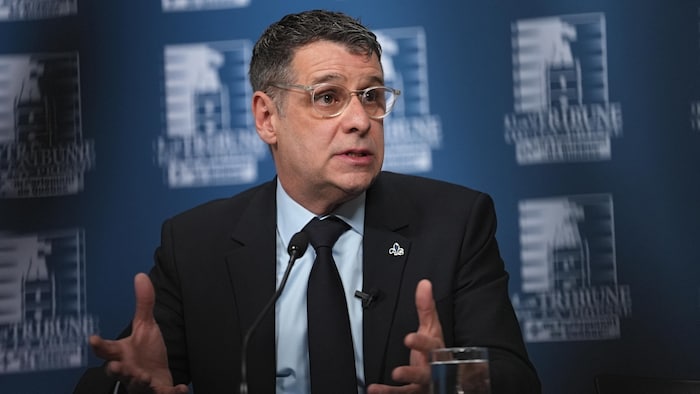 Éric Duhaime réponde à des questions des journalistes assis à un bureau.