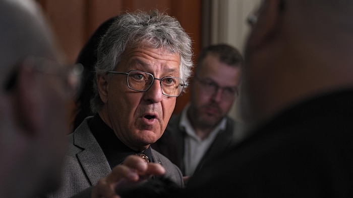 Daniel Bernard s'adresse aux journalistes dans un corridor de l'Assemblée nationale.