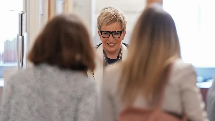 Suzanne Blais sourit à deux femmes devant elle.
