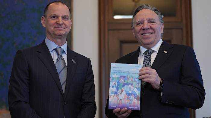 Éric Girard pose avec François Legault, qui tient un exemplaire du budget.
