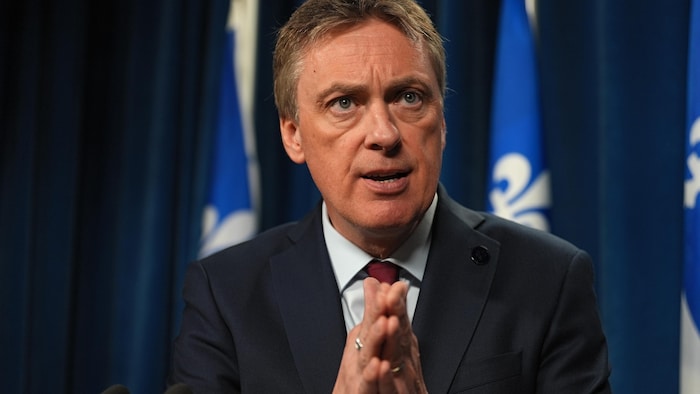 Marc Tanguay parle devant des drapeaux du Québec, lors d'une conférence de presse.