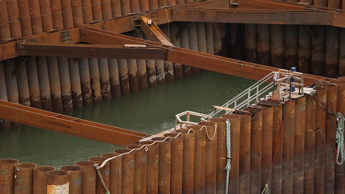 Un grand batardeau métallique inondé par les eaux du fleuve sur le chantier du pont de l'île d'Orléans.
