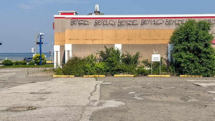 Un stationnement vide avec des graffitis sur un bâtiment.