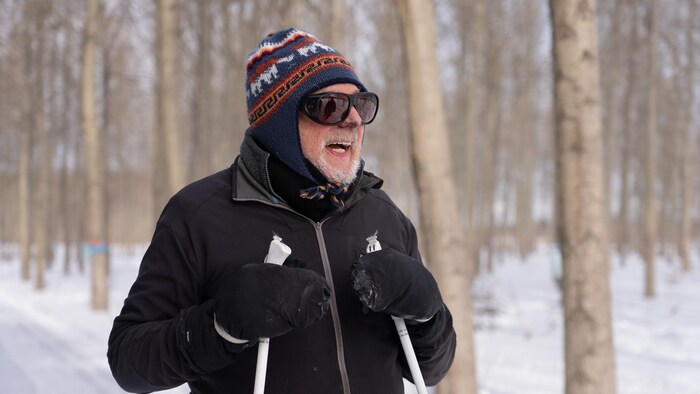 Portrait d'un homme portant une tuque et des lunettes de soleil. Il a de la suie qui noircie le bout de son nez.