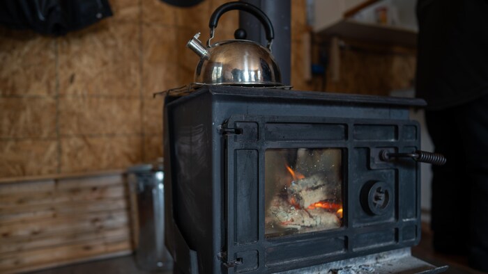 Un poêle à bois ancien dans un refuge, une bouilloire posée sur le dessus.