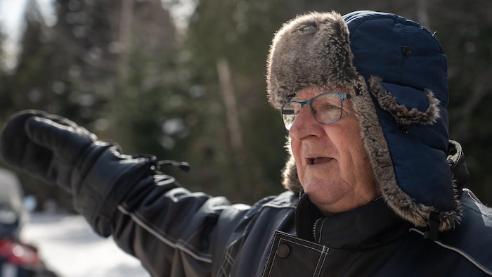 Janin Lévesque coiffé d'un chapeau de fourrure pointe sa mitaine dans les airs.
