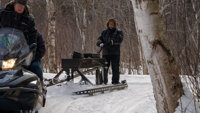 Dans un tournant, les hommes tracent les pistes à bord d'une motoneige.
