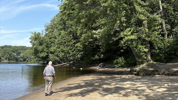 Marcel Pelchat marche sur la plage près de la rivière.