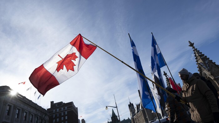 Un manifestant brandit un drapeau canadien à l'envers.