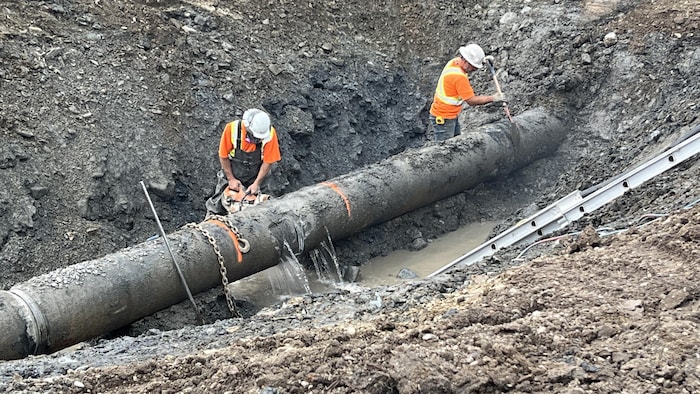 Des employés municipaux réparent une conduite d'aqueduc.