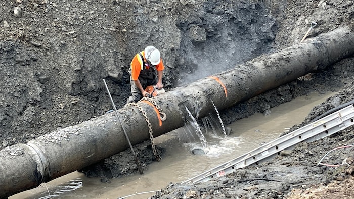 Un ouvrier répare une conduite d'eau.